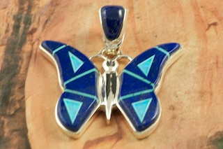 Stunning Butterfly Pendant features Genuine Blue Lapis inlaid in Sterling Silver. Beautiful Fire and Ice Lab Opal Accents. Free 18" Sterling Silver Chain with Purchase of Pendant. Designed by Navajo Artist Calvin Begay. Signed by the artist.
